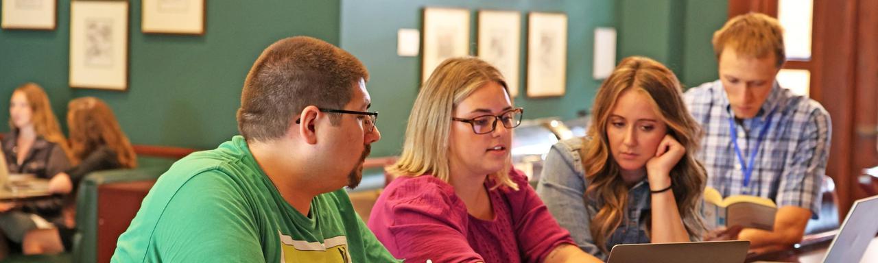 Teachers sitting together discussing work on a laptop